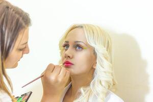 bonito joven mujer aplicando hacer arriba en belleza salón foto