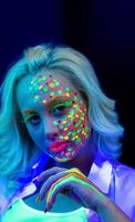 retrato de un mujer con pintado rostro, mujer con uv maquillaje en estudio, retrato de un mujer en carnaval mascarilla, el mujer es decorado en un ultravioleta polvo foto