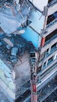 The removal of house wrecks after an earthquake. Dismantling of collapsed structures.Up view of excavator work with wrecks of ruined buildings. Vertical video