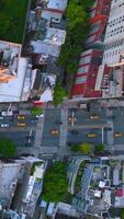 fliegend Über das Breitspur Straße und Kreuzung mit zahlreich Autos ziehen um entlang. Aussicht von das Dächer von Umgebung Häuser von oben. Vertikale Video