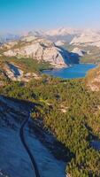 yosemite nationale parc paysage dans le des rayons de chaud brillant Soleil. magnifique rochers, pin arbre les bois et des lacs dans le panorama de célèbre parc de aérien voir. verticale vidéo video