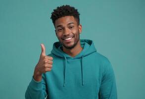 AI Generated Joyful man in teal hoodie giving a thumbs up, blue backdrop highlights him. photo