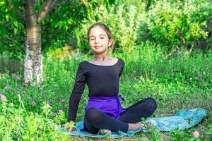 bonito niña haciendo yoga ejercicios, pequeño niña haciendo yoga ejercicios en el jardín foto