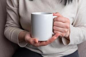 Hands of a woman hold a white clean mug, presenting a spotless surface for promoting unique mug designs. photo