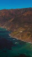 Eye-catching view of the rocks on the shore of California. Algae accumulation on the surface of sea-green water. Aerial perspective. Vertical video