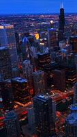 Breath-taking view of Chicago cityscape full of evening lights at dusk. Amazing metropolis at foreground. Aerial perspective. Vertical video