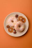 Delicious sweet bright donuts with cream on a plain background photo