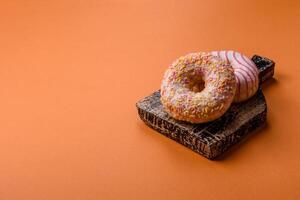 Delicious sweet bright donuts with cream on a plain background photo