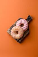 Delicious sweet bright donuts with cream on a plain background photo