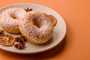 Delicious sweet bright donuts with cream on a plain background photo