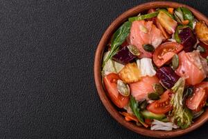 Delicious juicy salad with salmon, tomatoes, cucumber, herbs, pumpkin seeds photo