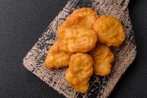 Delicious fresh crispy chicken nuggets on a dark concrete background photo