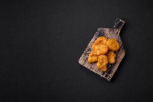 Delicious fresh crispy chicken nuggets on a dark concrete background photo