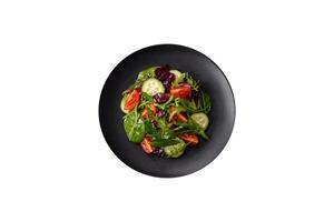 Delicious fresh salad with arugula, spinach, cucumber and cherry tomatoes in a ceramic plate photo