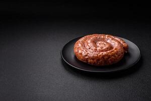 Delicious grilled sausage in the form of a ring with salt, spices and herbs photo