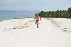 young muscular man exercising on the beach, young muscular man doing bodibuilding exercises on the beach, athletic young man on the beach photo