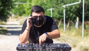 DJ con auriculares y mezclador en el parque, el DJ a trabajo foto