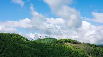 Natur Zeit Ablauf ziehen um Wolken Über Wald und schneebedeckt Berg im Hintergrund video