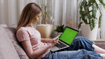 Female person using mockup laptop working remotely at home, online shopping. Manager hands scrolling touchpad surfing in internet looking information online. Chroma key computer, smartphone video