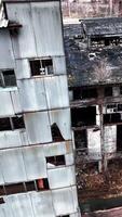 Deserted and solitary industrial zone of a plant destroyed with time. Abandoned territory dangerous for visiting. View from above. Vertical video