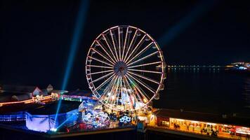 Illuminated Ferris wheel at night with vibrant lights and festive atmosphere at a seaside amusement park in Backpool, England. photo