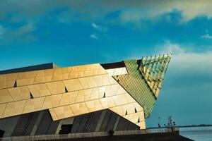 Modern architectural building with geometric facade against a blue sky with clouds. photo