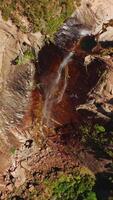 klein kreek vallend van steil klif in yosemite nationaal park, Californië, Verenigde Staten van Amerika. bijna droog waterval van antenne visie Aan zonnig heet dag. verticaal video