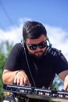 DJ con auriculares y mezclador en el parque, el DJ a trabajo foto