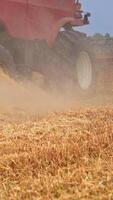 oogstmachine rijden in de veld. reusachtig wielen van een combineren roterend snel in de stof. gemaaid tarwe veld- dichtbij omhoog. verticaal video