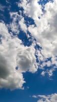 Cloudscape formation in the atmosphere. Amazing timelapse of white fluffy clouds moving softly on the sky and the sun shining above the clouds with beautiful rays. Vertical video