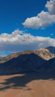 bianca morbido cumulo nuvole Soaring al di sopra di il bellissimo montagne. Cloudscape lancio ombre su il rocce. fantastico azzurro cieli a sfondo. verticale video