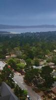 Dramatic dark stormy skies over the beautiful marine city of Carmel, California, USA. Drone flying low over the tree tops. Vertical video