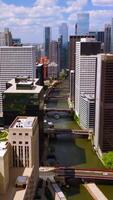 Fantastic buildings of great Chicago. Drone flying over the buildings with green areas on tops, over the river with multiple bridges on. Cloudy sky at backdrop. Vertical video