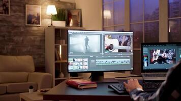 Back view of content creator using modern software for post production in home office during night time. video