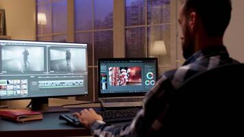 Back view of content creator working in home office during night time. Video editor in home office.