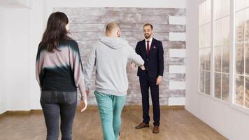 Real estate agent shows new apartment to young couple. Man shaking hands with real estate agent. video