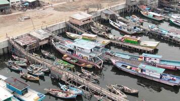 antenn antal fot av båtar dockad på de pir i en slum och tätt befolkad område i cilingcing, tanjung priok, norr jakarta - perahu kayu bersandar di dermaga wilayah kumuh padat penduduk 4k Drönare video