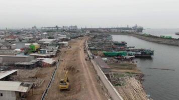 antenne beeldmateriaal van boten aangemeerd Bij de pier in een sloppenwijk en dicht bevolkt Oppervlakte in cirkelen, tanjung prik, noorden Jakarta - perahu kayu bersandar di dermaga wilayah kumuh padat penduduk 4k dar video