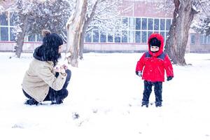 mother and the little boy are playing in winter park, mother and cute boy photo