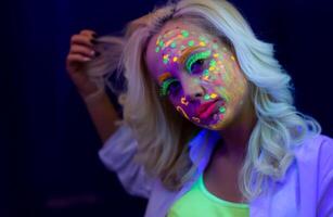 retrato de un mujer con pintado rostro, mujer con uv maquillaje en estudio, retrato de un mujer en carnaval mascarilla, el mujer es decorado en un ultravioleta polvo foto