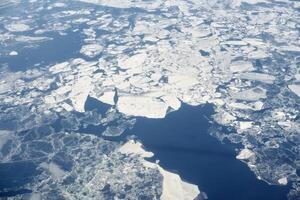 Aerial view from airplane window over clouds to frozen sea with north steam gas pipeline underwater photo