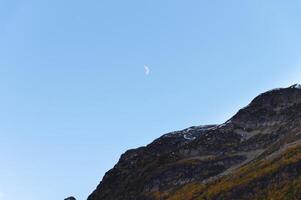 claro tiempo de día azul cielo, montañas y menguante blanco Luna foto