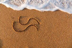 edge of the surf on a sandy beach. drawing of two waves on a background of sand photo