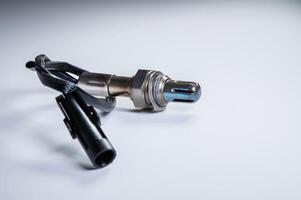 The oxygen sensor is a new lambda sensor. Spare parts on the car on a gray gradient background photo