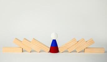 The concept of the domino effect, the fall of the Russian economy. A wooden man with the symbol of the Russian flag and a fallen domino around him. Sanctions against Russia. photo