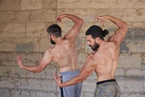 the two young muscular mans doing bodibuilding exercises in the city, two muscular young mans, athletic young mans in the park photo