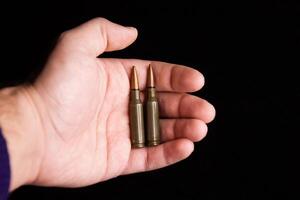 bullets in a hand, hand holding a bullet on black background photo