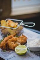 Crispy fried fish and chips with tartar sauce and lime photo