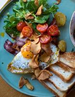 Breakfast with fried eggs, bacon, toasts and vegetable salad photo
