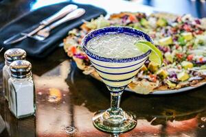 Cocktail with lime and olives on a table in a restaurant photo